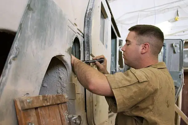 U.S. Mechanic works on replacing HMMWV fuel tank salvaged from destroyed vehicle in Iraq.