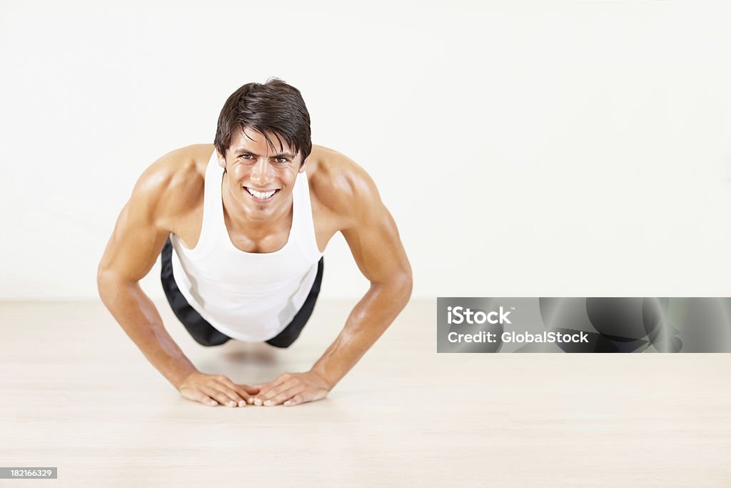 Happy young athletic guy doing push ups at a gym Smiling young athletic man doing push ups at a gym 20-24 Years Stock Photo