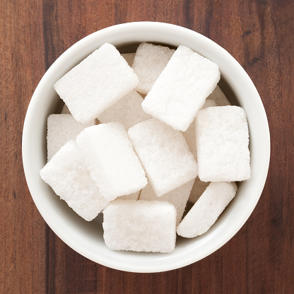 White granulated sugar and refined sugar cubes close-up in the kitchen.