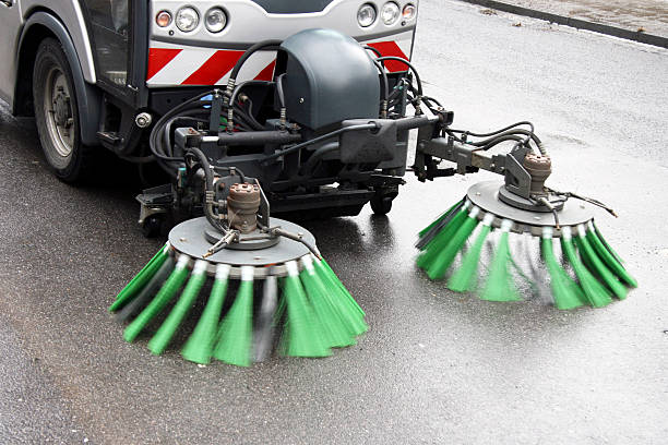 Yellow bristles of street sweeping machine in action against wet asphalt