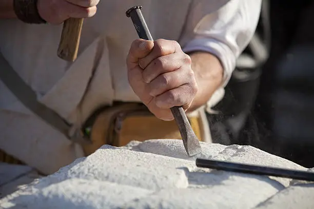 Carving stone in the sun with hammer and chisel