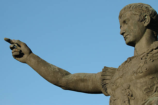Roman emperor Caesar Augustus pointing finger An isolated (on blue background) view from the bottom of a roman emperor Caesar Augustus statue made of green material with his finger pointing in one direction meaning power and commitment augustus caesar photos stock pictures, royalty-free photos & images