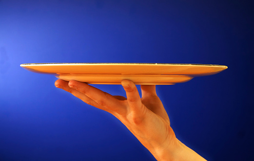 female hand holding up a platter on blue background.