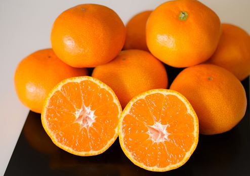 Peeled orange divided into slices on a board , peeling a ripe and juicy orange orange