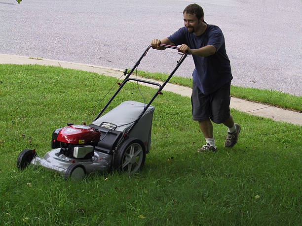 man mowing overgrown yard stock photo