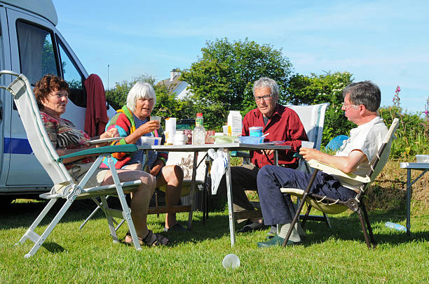 Breakfast on campsite with four seniors and motor home stock photo