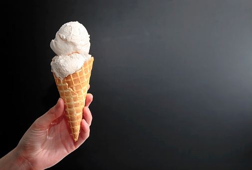 A hand holding an ice cream cone.