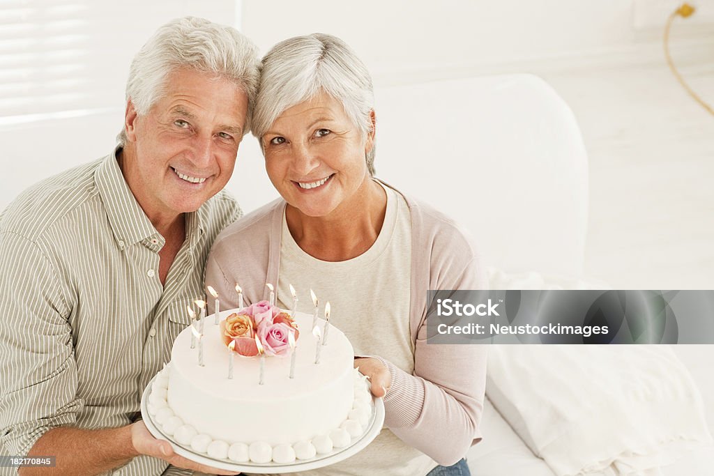 Coppia senior con torta di anniversario - Foto stock royalty-free di 65-69 anni