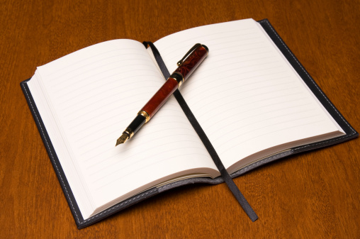 Small leather-bound journal and fountain pen.