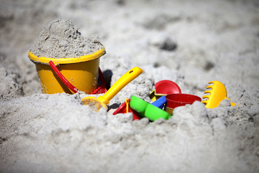 A close-up of a bucket and shovel in the sand of a beach