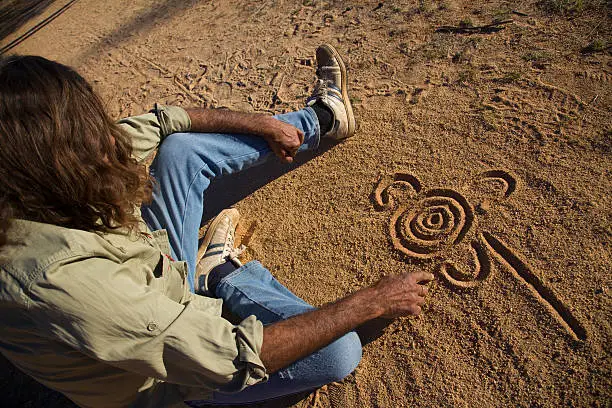 Photo of Aboriginal man drawing in the dirt