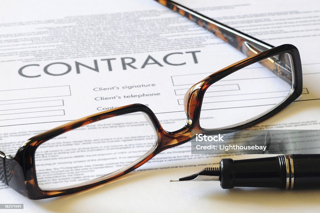 Pair of reading glasses resting on a contract with pen A pair of reading glasses resting on a contract Authority Stock Photo
