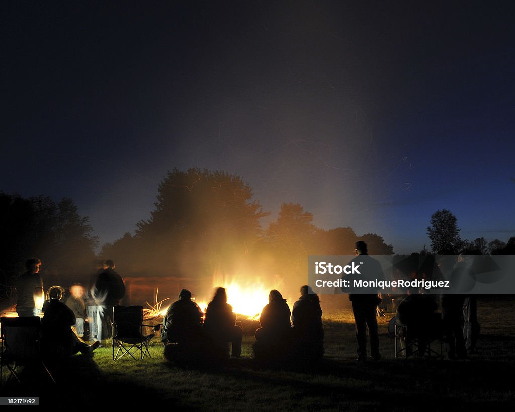 Gruppo di persone in tutto il Fuoco di accampamento - Foto stock royalty-free di Fuoco di accampamento