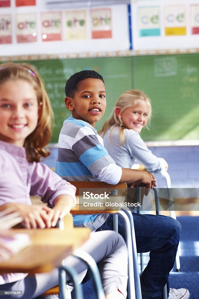 School boy sitting in classroom and looking behind Portrait of a happy school children sitting in classroom 10-11 Years Stock Photo