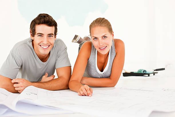 istock Smiling young couple lying on floor with blueprints 182171649