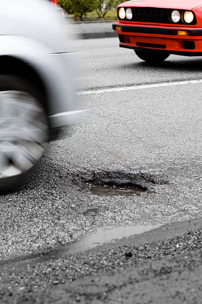 voiture des approches un nid-de-poule - pot hole street car hole photos et images de collection