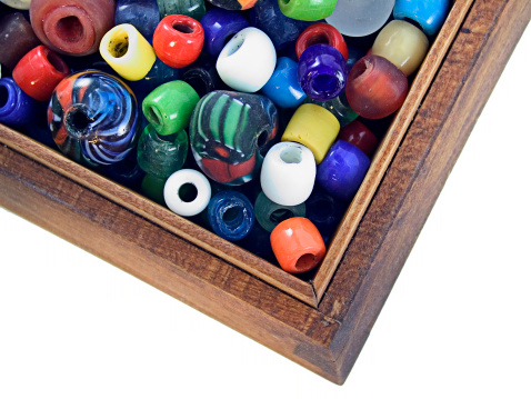 Colorful glass and clay African beads in a wooden box.