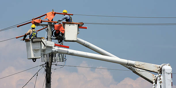 Two workers in a crane repairing a power pole stock photo
