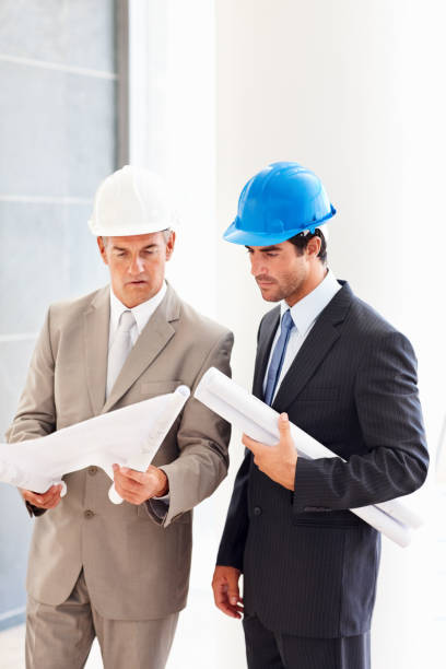 istock Business colleagues holding blueprints and discussing for project 182173656