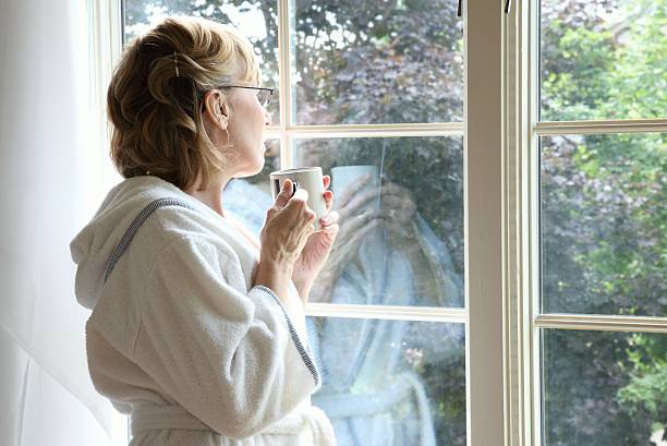 Woman Drinking Coffee Looking Out Window stock photo