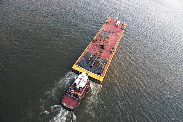 Tugboat pushing a barge up a river.