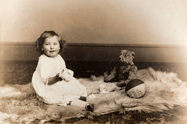 Vintage Baby Girl Portrait "Vintage black and white photograph of a baby girl sitting on an animal skin rug, with a teddy bear and toys, circa 1910. Some dust and scratches that reflect age of original image. See my vintage images lightbox, including similar baby boy shot..." teddy bear photos stock pictures, royalty-free photos & images