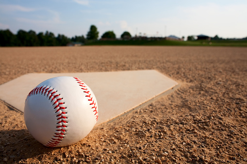 A wide-angle view of a new baseball on home plate of a baseball field.