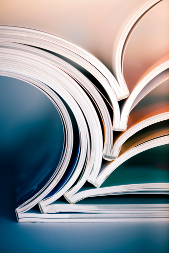 Abstract shot of open magazines piled on table. Macro shot with shallow DOF