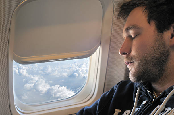 Photograph of a young man sleeping on plane in flight