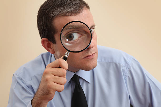 businessman looking at camera through a magnifying glass - vergroting stockfoto's en -beelden
