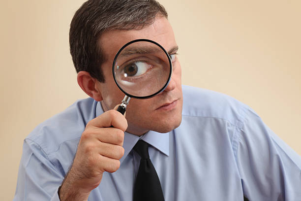 Businessman looking at camera through a magnifying glass stock photo