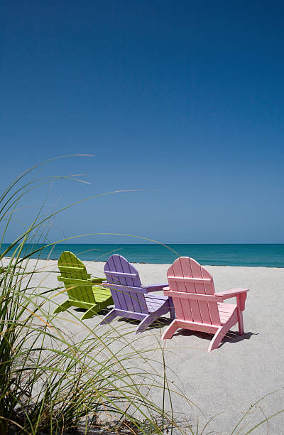 istock Back view of three pastel colored beach chairs on sand 182175300