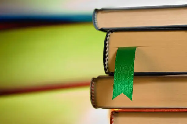 Photo of Close-up of green ribbon bookmark in a stack of books