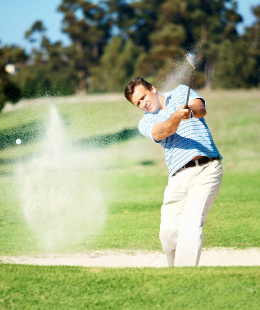 mature golfeur frapper dans un bunker - golf playing men ball photos et images de collection