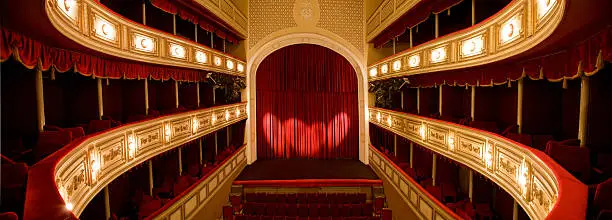 Classical Theater with Red stage curtain with arch lights and shadows.