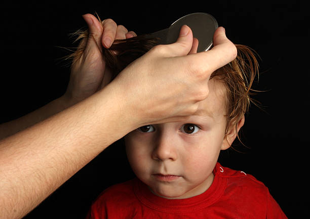 Combing a three year old boy's hair with a nit comb to remove headlice ( isolated on black )Please see some similar images from my portfolio :