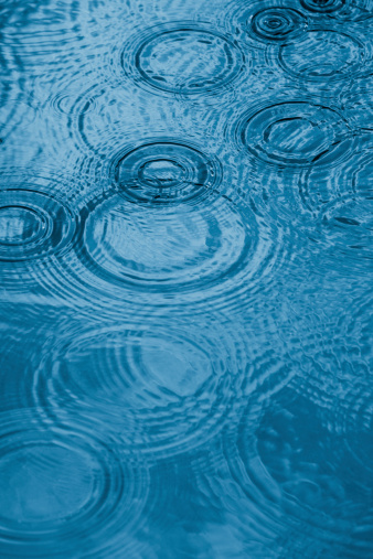 Close up of a water surface with rain drops falling.Monochrome blue