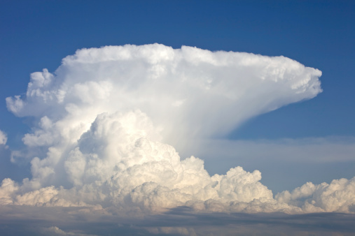 This is a complete anvil cloud consisting of mostly ice above a thunderstorm. The rising air is expanding and spreading the cloud as it hits the bottom of the stratosphere. Shot in the evening with the sun at my back showing the deep blue color in the sky above the storm.