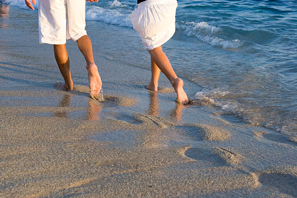 Smiling middle-aged interracial couple holding hands, walking and spending honeymoon on seaside