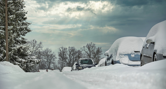 Enchanting winter landscape, where a group of vehicles has been blanketed by a fresh layer of snow that indicates a winter storm or a blizzard recently passed through the area