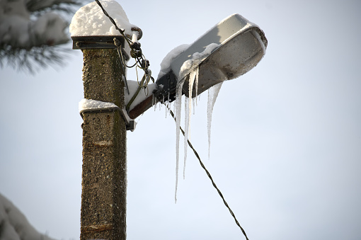 Close-up of an electrical post blanketed in snow with icicles adorning its sides, wintry atmosphere of the scene