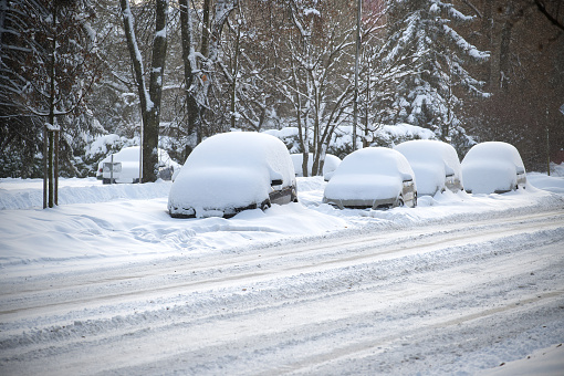 Winter's day with multiple cars, some cars are almost entirely buried by the snow
