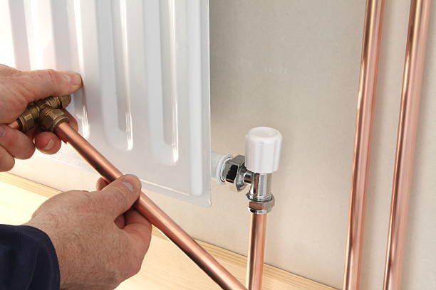 A plumber installing a new radiator Plumbing in a new central heating radiator. radiator heater photos stock pictures, royalty-free photos & images