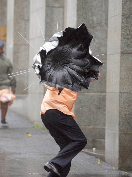 A man battles with his umbrella in a windy street in the rain.