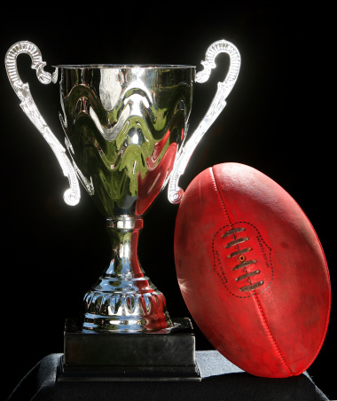 A trophy and an AFL ball on black background