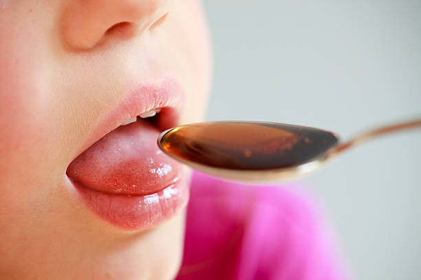 ребенок, принимая лекарство от ложка — крупный план - cough medicine spoon medicine liquid стоковые фото и изображения