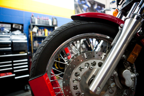 a shot of the front wheel of a motorcycle (and brake rotor) up on a workbench