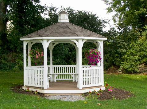 Pretty gazebo decorated with hanging baskets of petunias located in a quiet spot