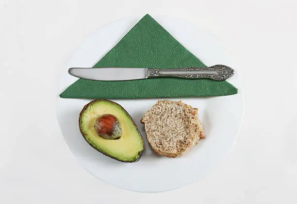 avocado and brown bread isolated on white with plate,napkin and knife