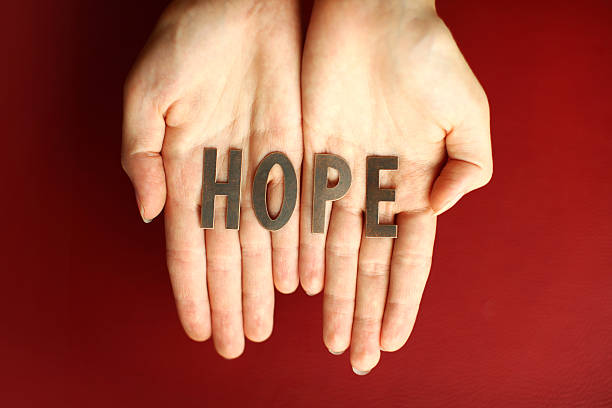 istock Pair of open hands on a red background holding the word HOPE 182178079